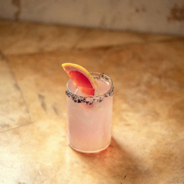 Cocktail con una rodaja de toronja, con un escarchado oscuro
